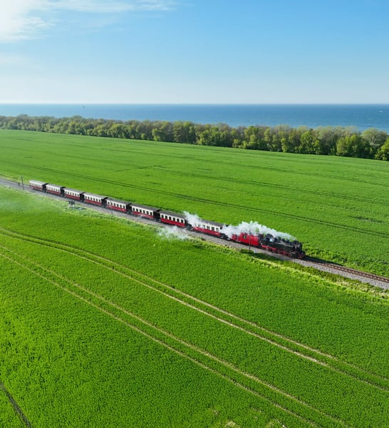 Historische Dampfbahn Molli fährt durch grüne Felder nahe der Ostseeküste