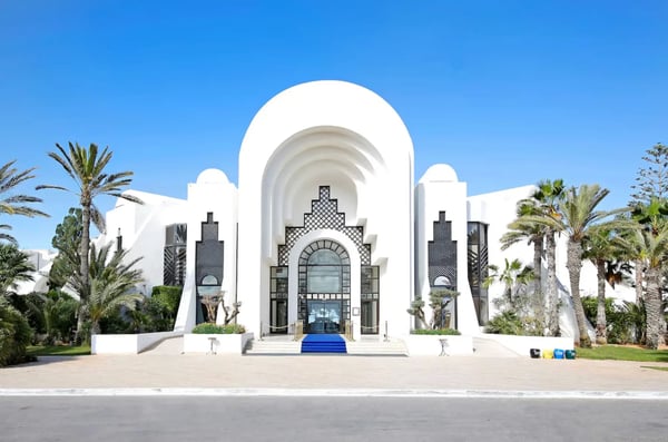 Weiße Hotelanlage im orientalischen Stil mit Palmen und Eingang im Resort auf Djerba.