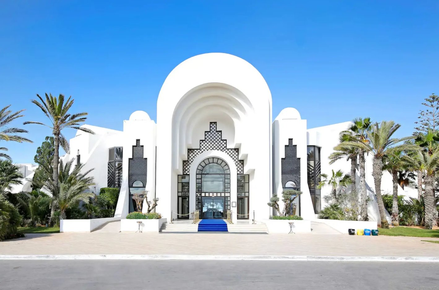 Weiße Hotelanlage im orientalischen Stil mit Palmen und Eingang im Resort auf Djerba.