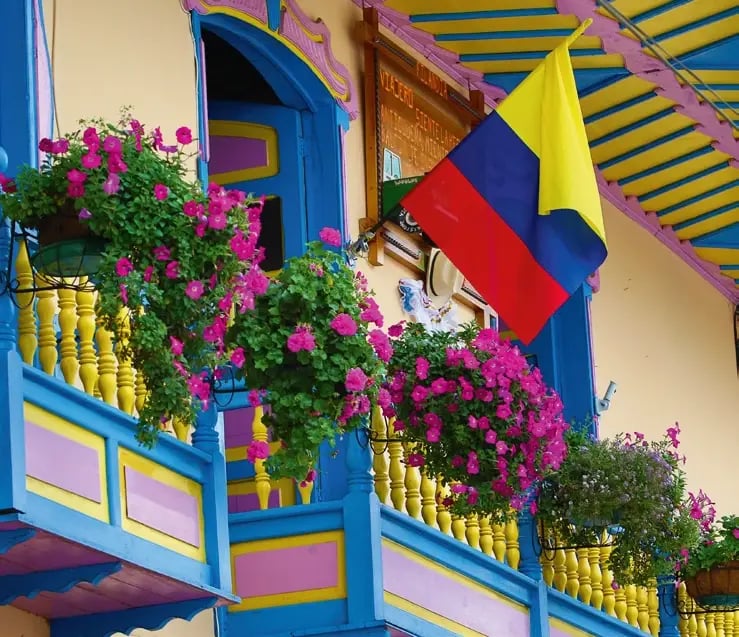 Farbenfroher Balkon mit blühenden Pflanzen und kolumbianischer Flagge.