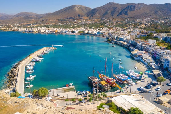 Panoramablick auf Agios Nikolaos mit Hafen, Booten und umliegenden Bergen bei klarem Wetter