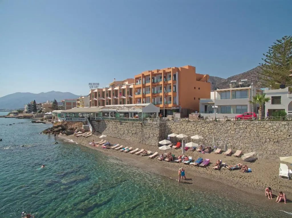 Strandhotel an der Küste von Kreta mit Sonnenliegen, Kiesstrand und klarem Meer