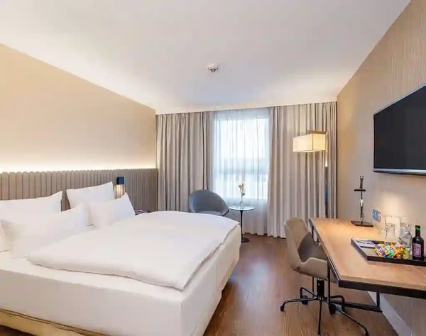 Modernes Hotelzimmer mit Doppelbett, Schreibtisch, Fernseher und grossem Fenster