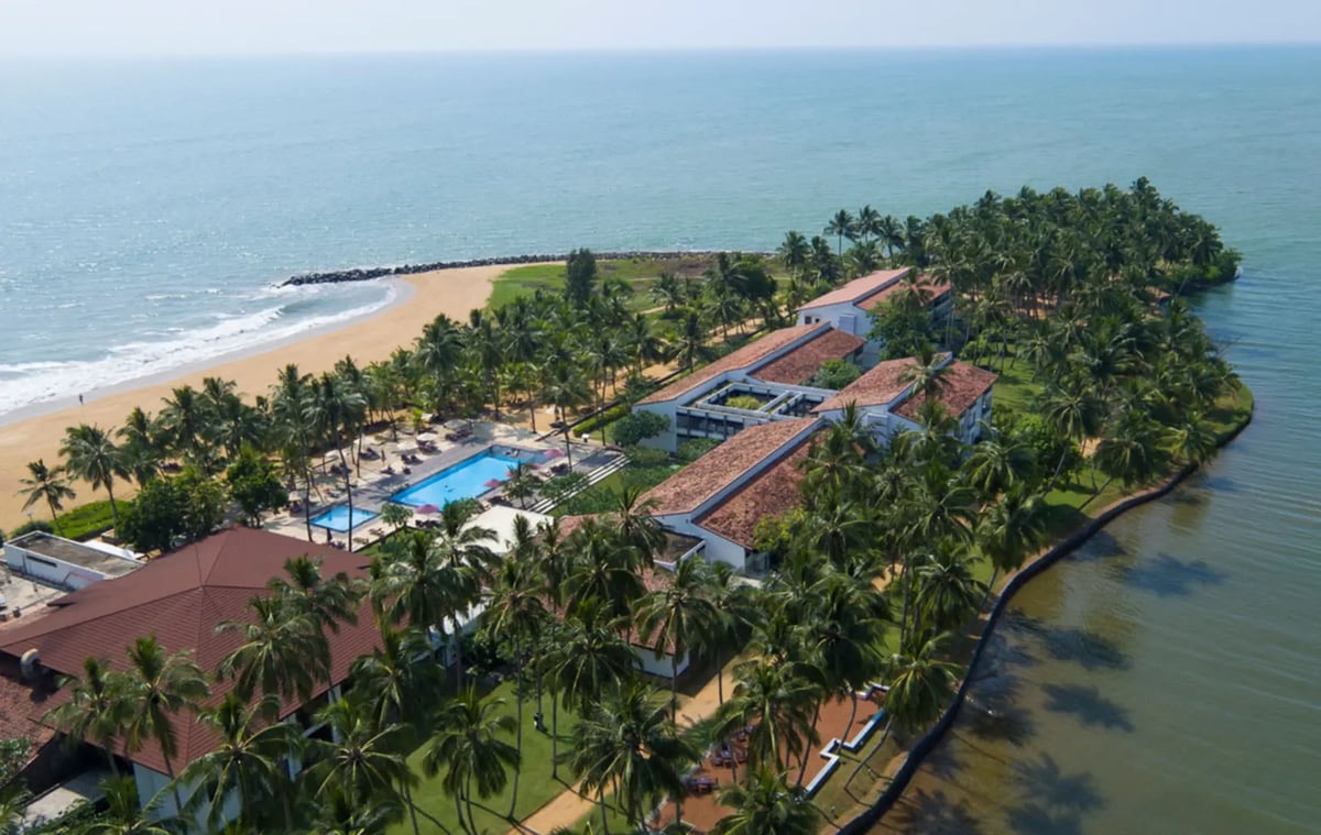Tropisches Strandresort Avani Kalutara in Sri Lanka, umgeben von Palmen zwischen Meer und Lagune.