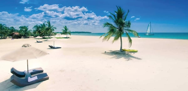 Weißer Sandstrand mit Palmen und türkisfarbenem Meer am Uga Bay Resort in Sri Lanka.