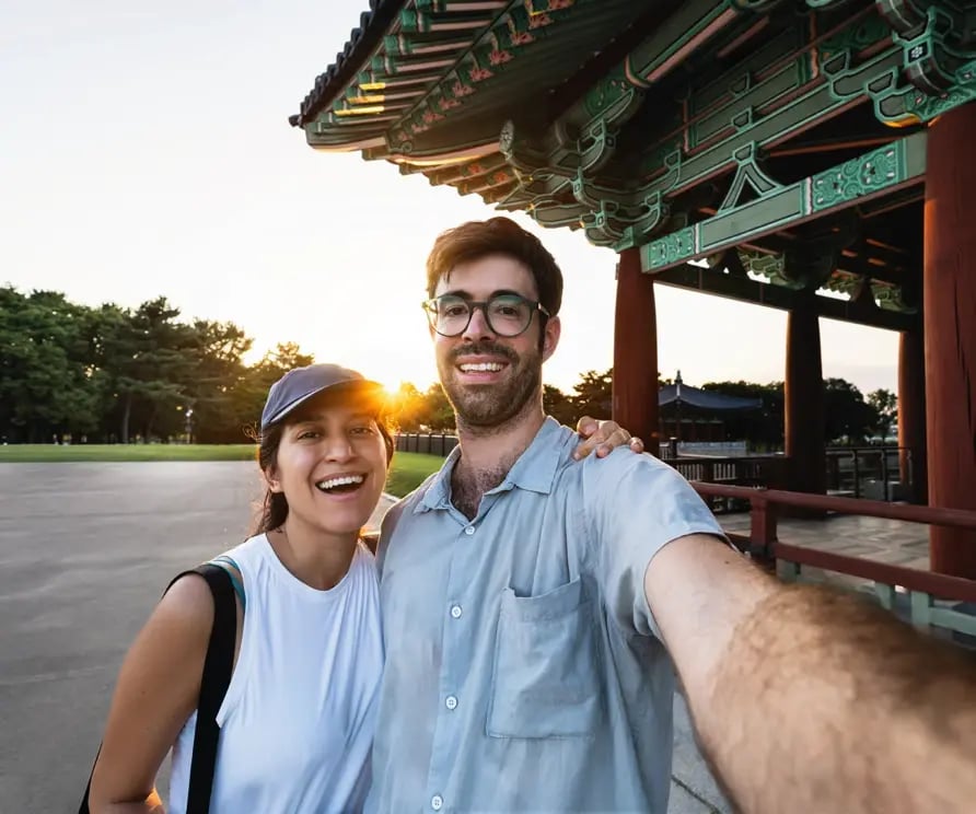 Fröhliches Paar macht ein Selfie vor einem traditionellen koreanischen Pavillon.