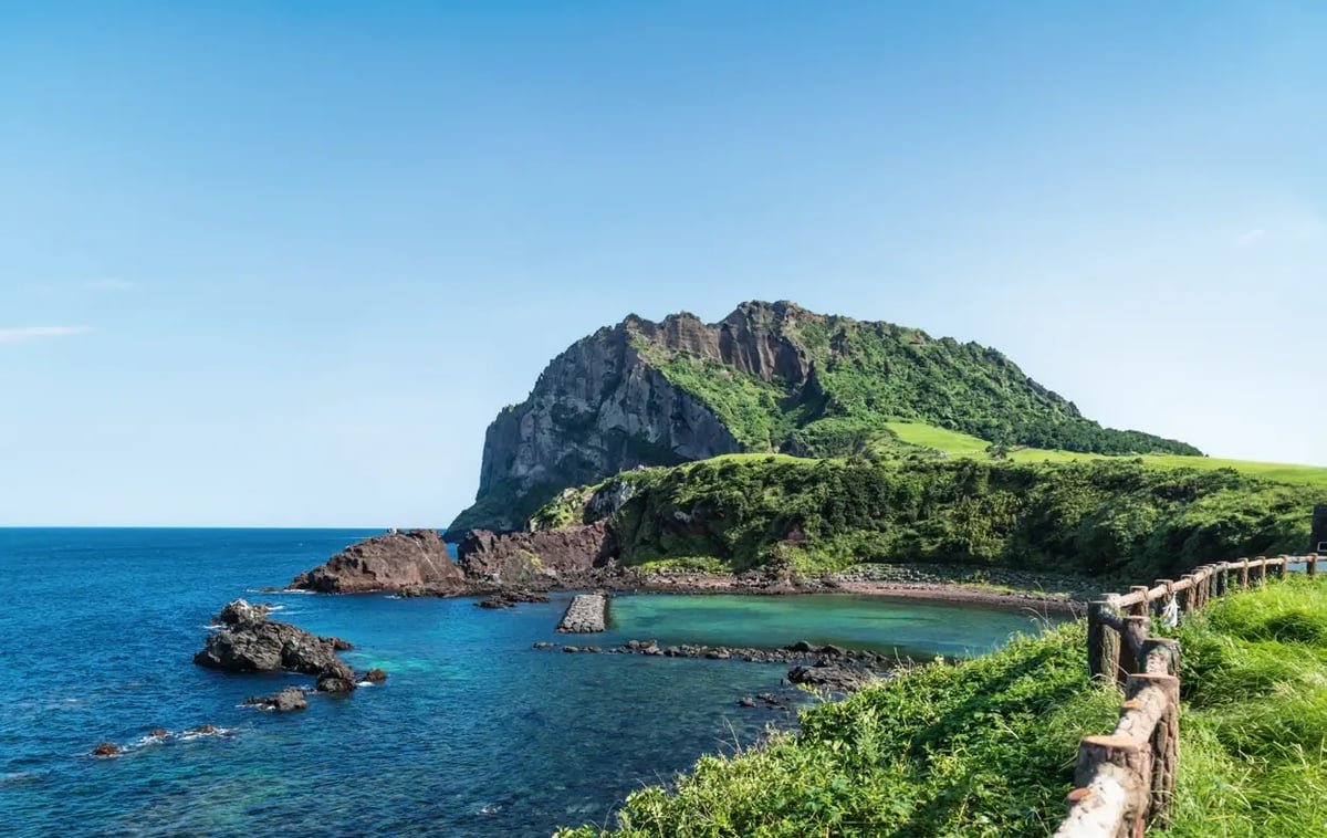 Vulkankrater Seongsan Ilchulbong auf Jeju mit steiler Küste und türkisblauem Meer.