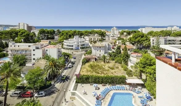 Moderne Hotelanlage mit Pool umsäumt von Palmen auf Mallorca.