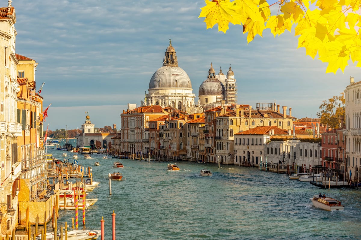 Blick auf den Canal Grande in Venedig mit der Basilika Santa Maria della Salute und zahlreichen Booten im herbstlichen Licht.