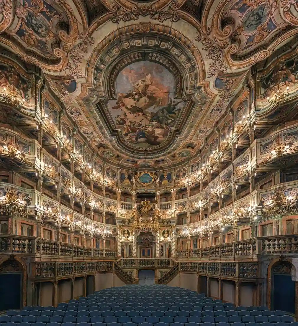 Prunkvoller Theatersaal mit reich verziertem Deckengemälde, goldenen Logen und Reihen blauer Sitze.