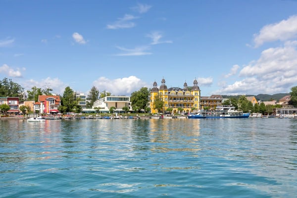 Uferansicht der Bucht von Velden mit Seepromenade, Booten und historischen Gebäuden