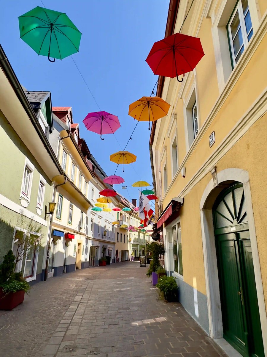 Fussgängerzone in Villach mit bunten Hängeschirmen zwischen historischen Gebäuden