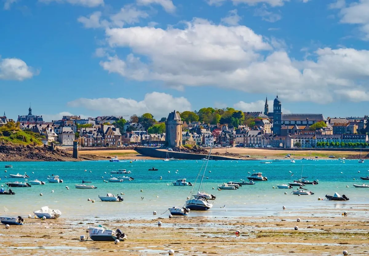 Historische Altstadt von Saint-Malo mit Hafen, Stadtmauer und zahlreichen Booten bei Ebbe.