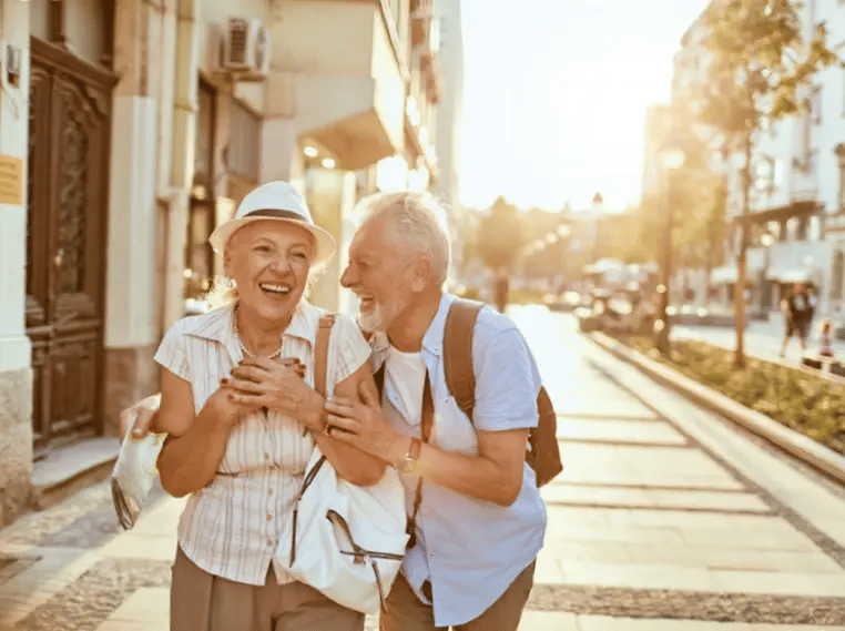 Couple de seniors souriant se promenant de bonne humeur dans une ruelle ensoleillée de la vieille ville