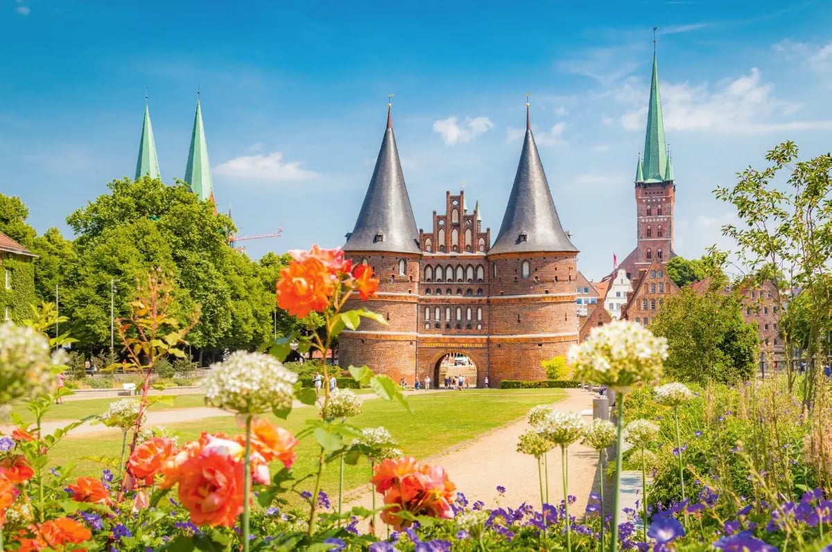 Das Holstentor in Lübeck, umgeben von Blumen und Grünanlagen.