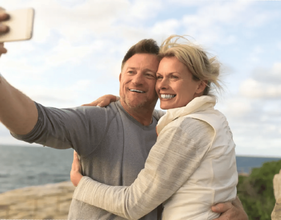 Glückliches Paar macht ein Selfie mit Meerblick während der Reise.