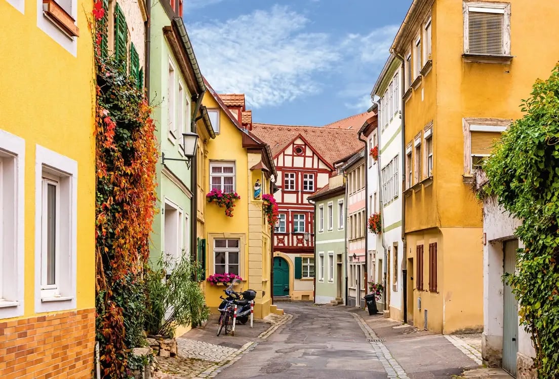 Malerische Altstadtgasse in Bamberg mit farbenfrohen Häusern, Fachwerkfassaden und Blumenschmuck.