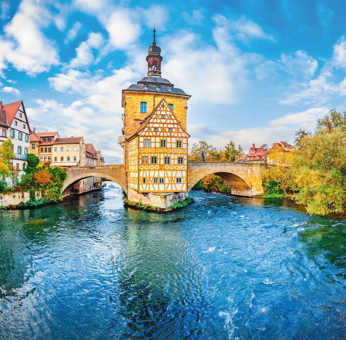 Altes Rathaus auf einer Brücke über der Regnitz in Bamberg mit historischem Fachwerk und Flusslandschaft.