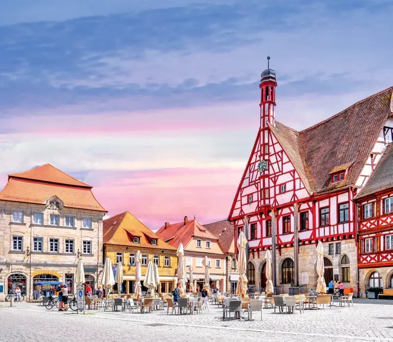 Historischer Marktplatz in Forchheim mit Fachwerk-Rathaus, Cafés und Sitzplätzen im Freien.