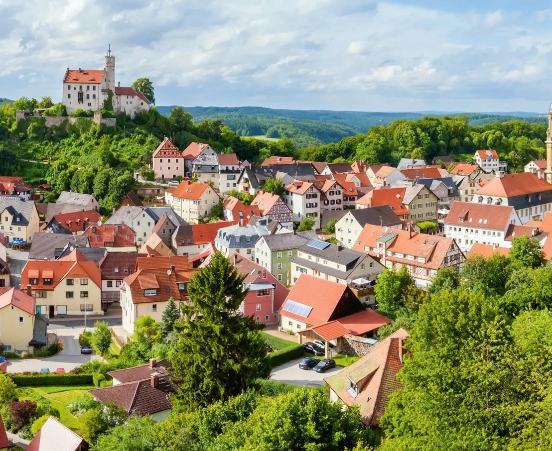 Blick über Gößweinstein mit Burg, Fachwerkhäusern und grüner Hügellandschaft der Fränkischen Schweiz.