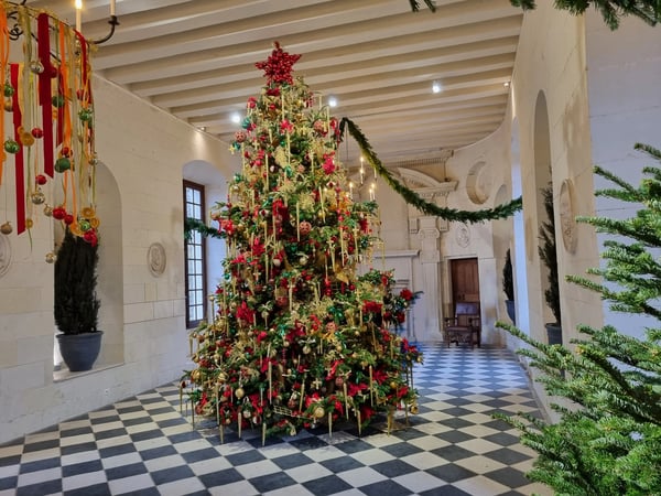 Festlich geschmückter Weihnachtsbaum in einem Schloss mit historischer Architektur.