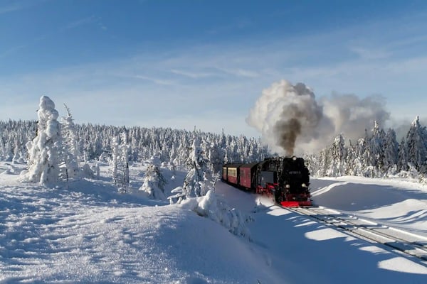 Dampflok der Brockenbahn fährt durch verschneite Winterlandschaft im Harz.