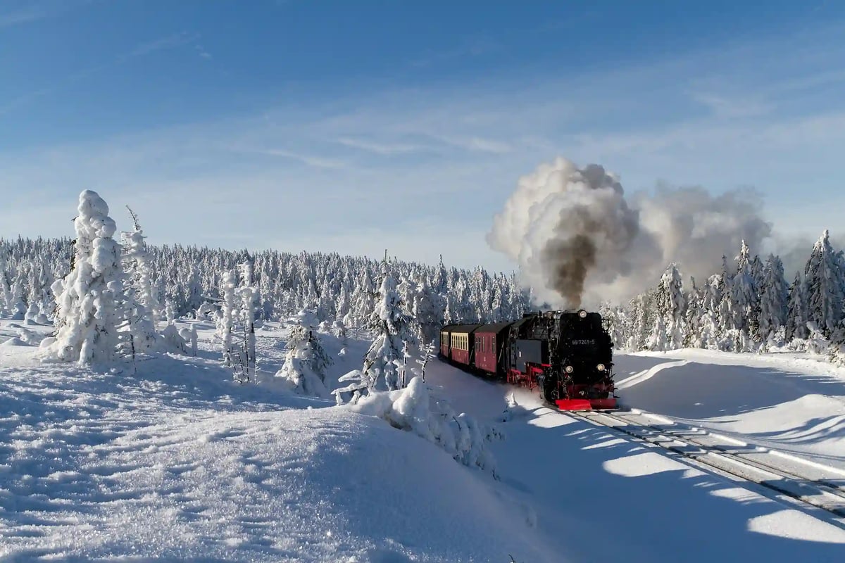 Dampflok der Brockenbahn fährt durch verschneite Winterlandschaft im Harz.