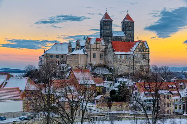 Historische Altstadt von Quedlinburg mit Fachwerkhäusern und Schloss im Winter.