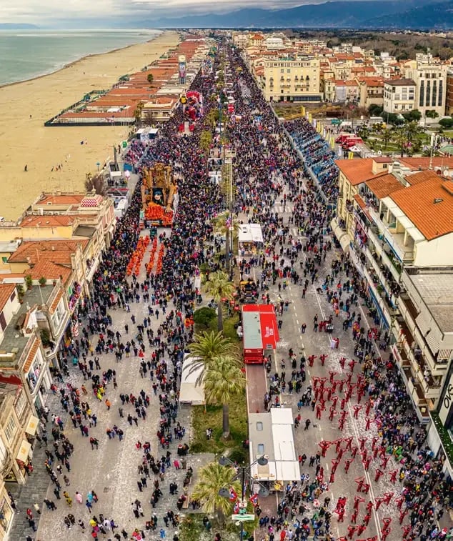 Luftaufnahme des Karnevalsumzugs in Viareggio mit Festwagen, Zuschauern und Strandpromenade.