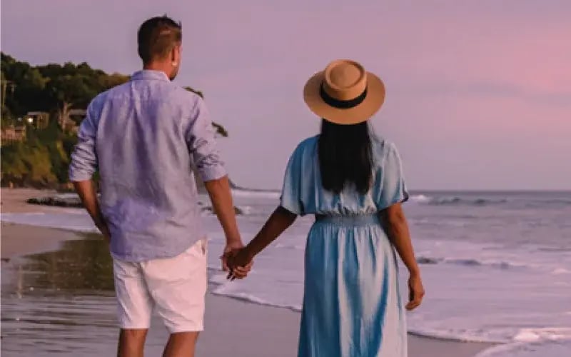 Paar spaziert Hand in Hand entlang eines karibischen Sandstrandes