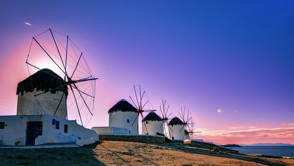 Traditionelle Windmühlen auf Mykonos bei Sonnenuntergang mit Blick auf das Meer