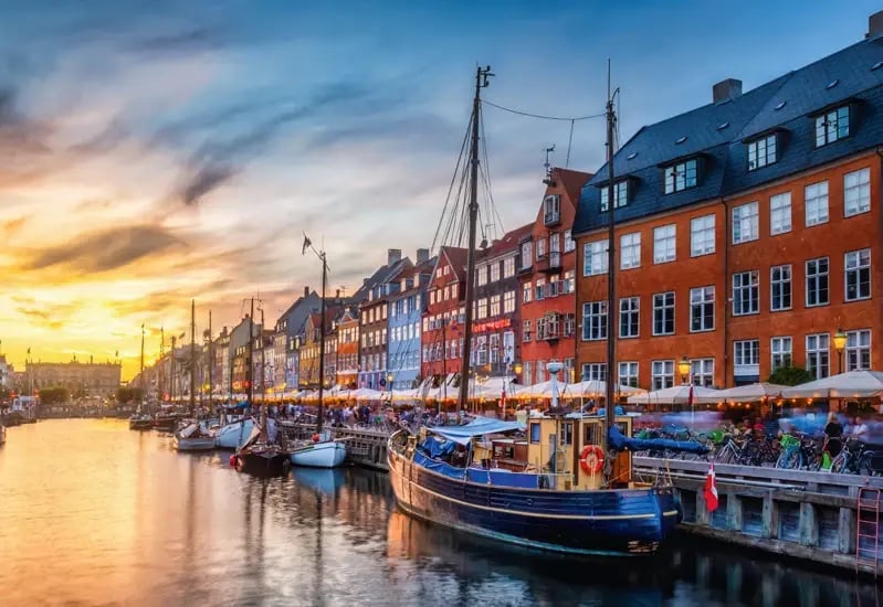 Nyhavn in Kopenhagen mit historischen Häusern, Segelschiffen und stimmungsvoller Abendsonne.