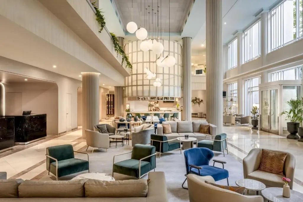 Hall d hôtel moderne et lumineux avec coins salon colonnes hautes et grandes fenêtres
