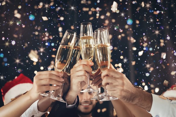 Personnes trinquant avec des coupes de champagne devant un fond scintillant pour le Nouvel An