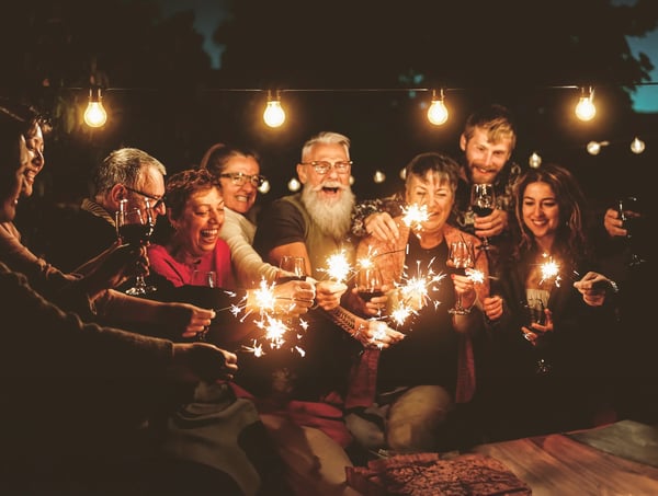 Groupe de personnes célébrant le Nouvel An avec des cierges magiques et des boissons le soir
