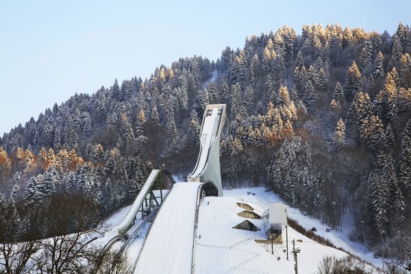Tremplin de saut à ski dans un paysage enneigé entouré de forêts hivernales