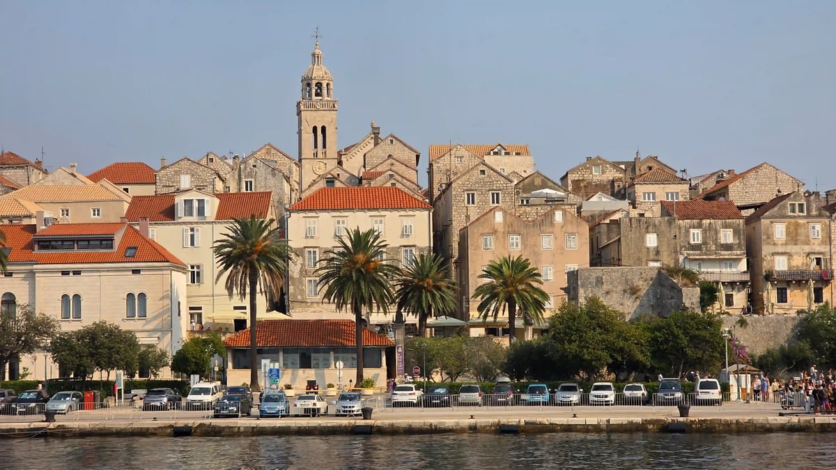 Maisons historiques aux toits rouges bordant le port d’une ville sur la côte dalmate