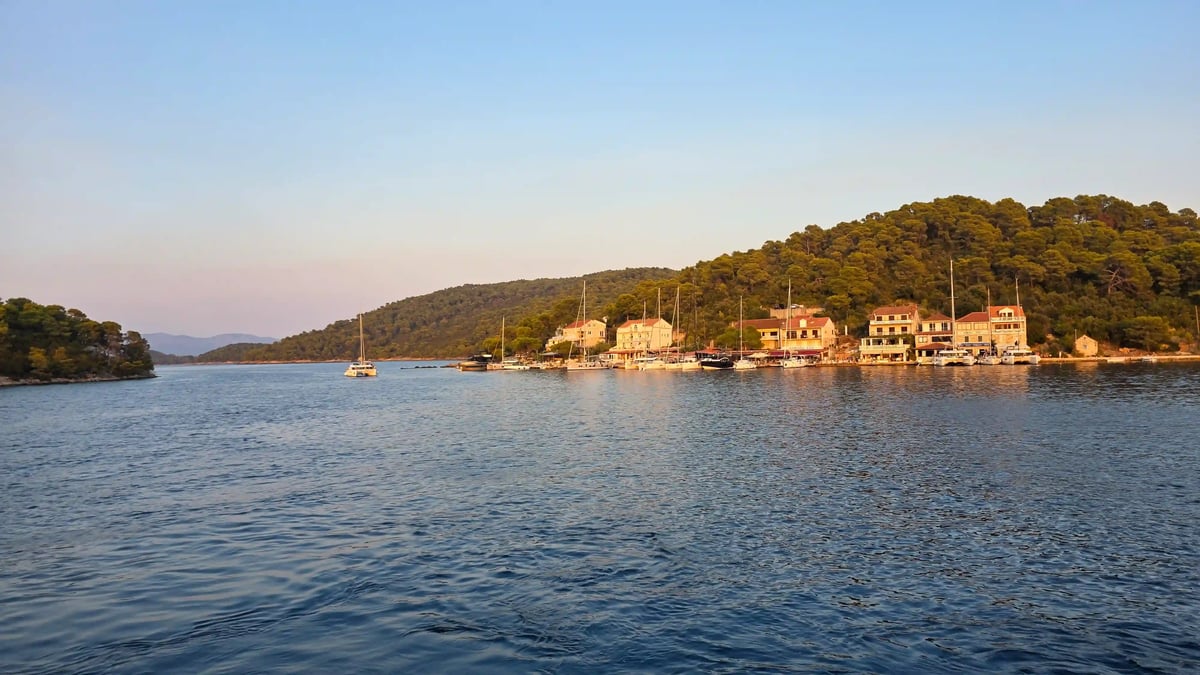 Petit port abrité aux eaux turquoise, entouré de collines verdoyantes en Dalmatie