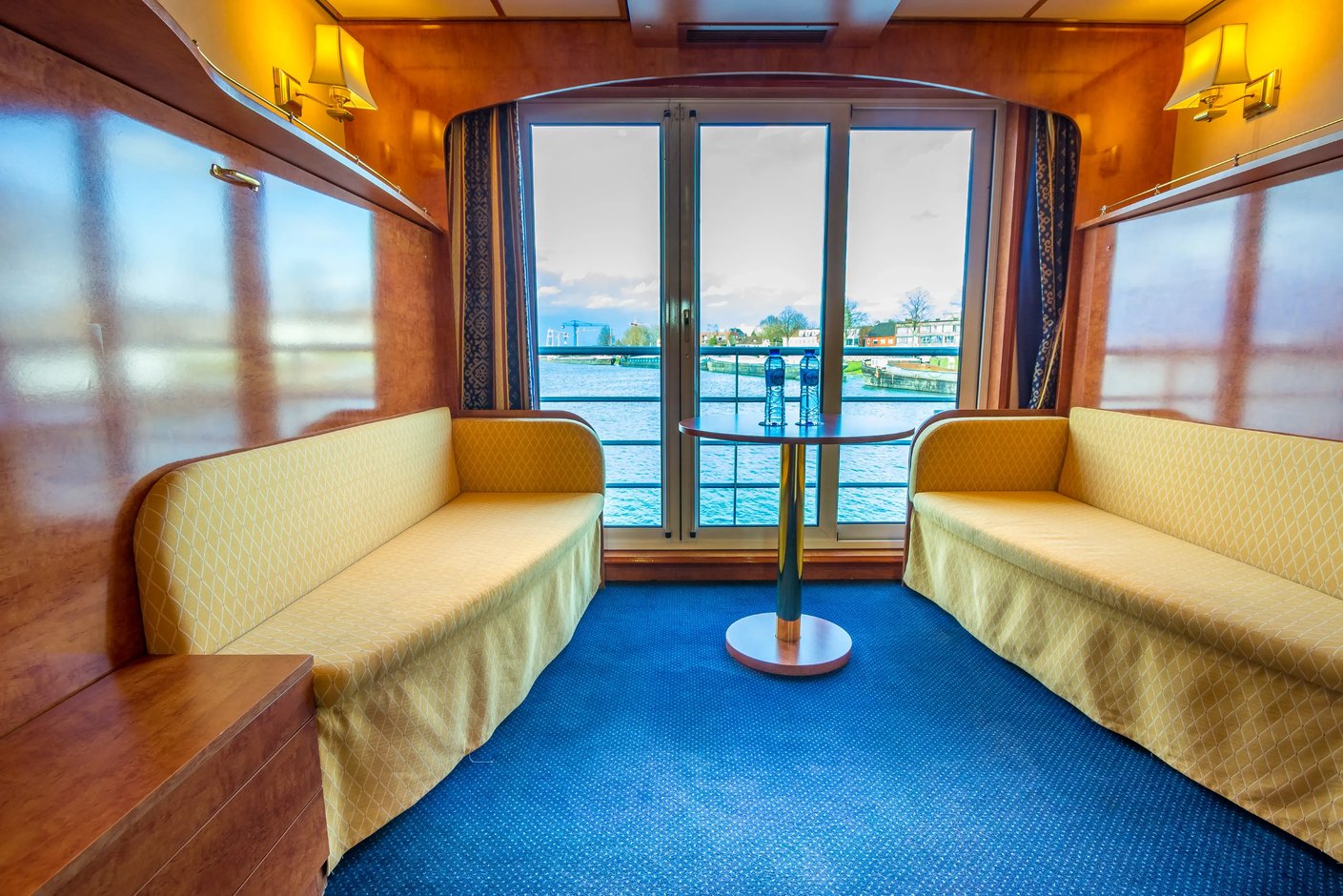 Cabine Serenade du MS Dutch Melody avec canapes face a face, petite table et balcon francais avec vue sur le fleuve.
