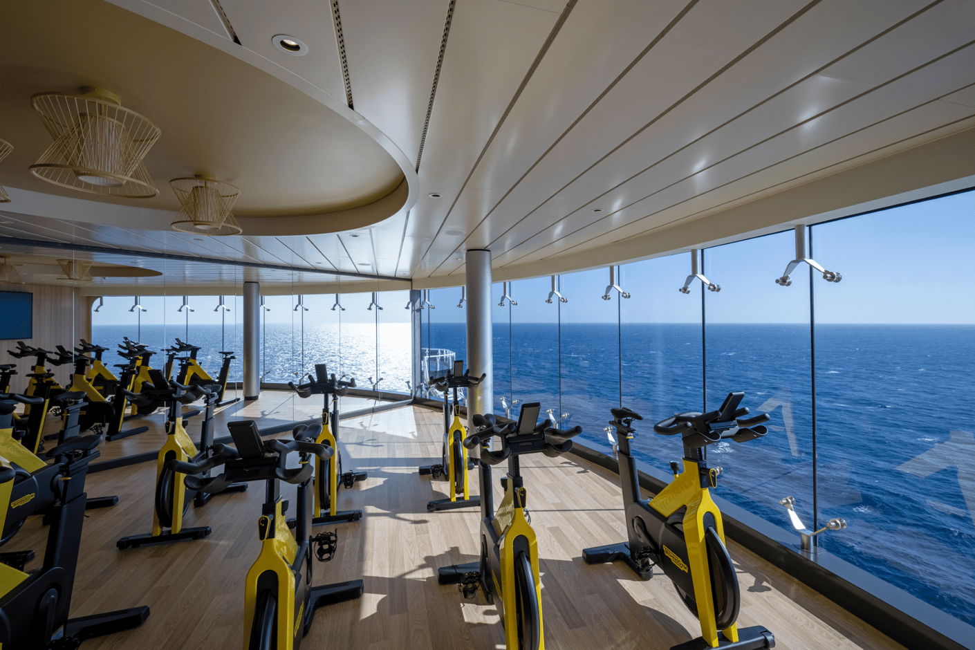 Fitnessbereich mit Spinningrädern und Panoramablick auf das Meer