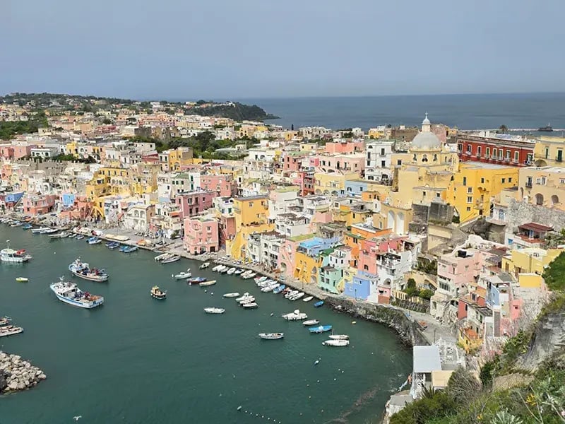 Bunte Küstenstadt mit Hafen, Booten und dicht stehenden Häusern am Meer