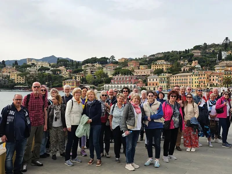 Reisegruppe vor bunter Küstenstadt mit Häfen und Hügeln im Hintergrund