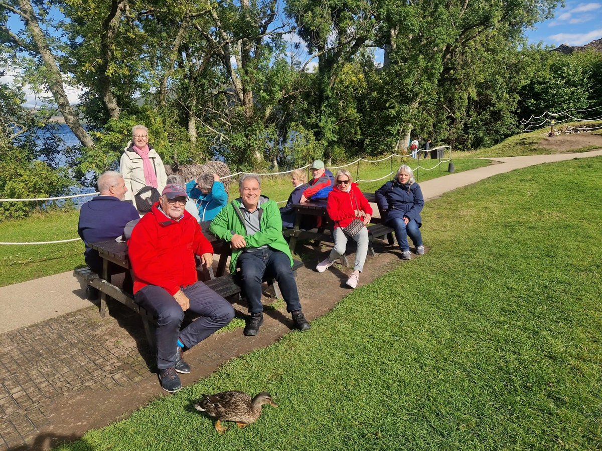 Reisegruppe bei einer Pause im Grünen am Loch Lomond.