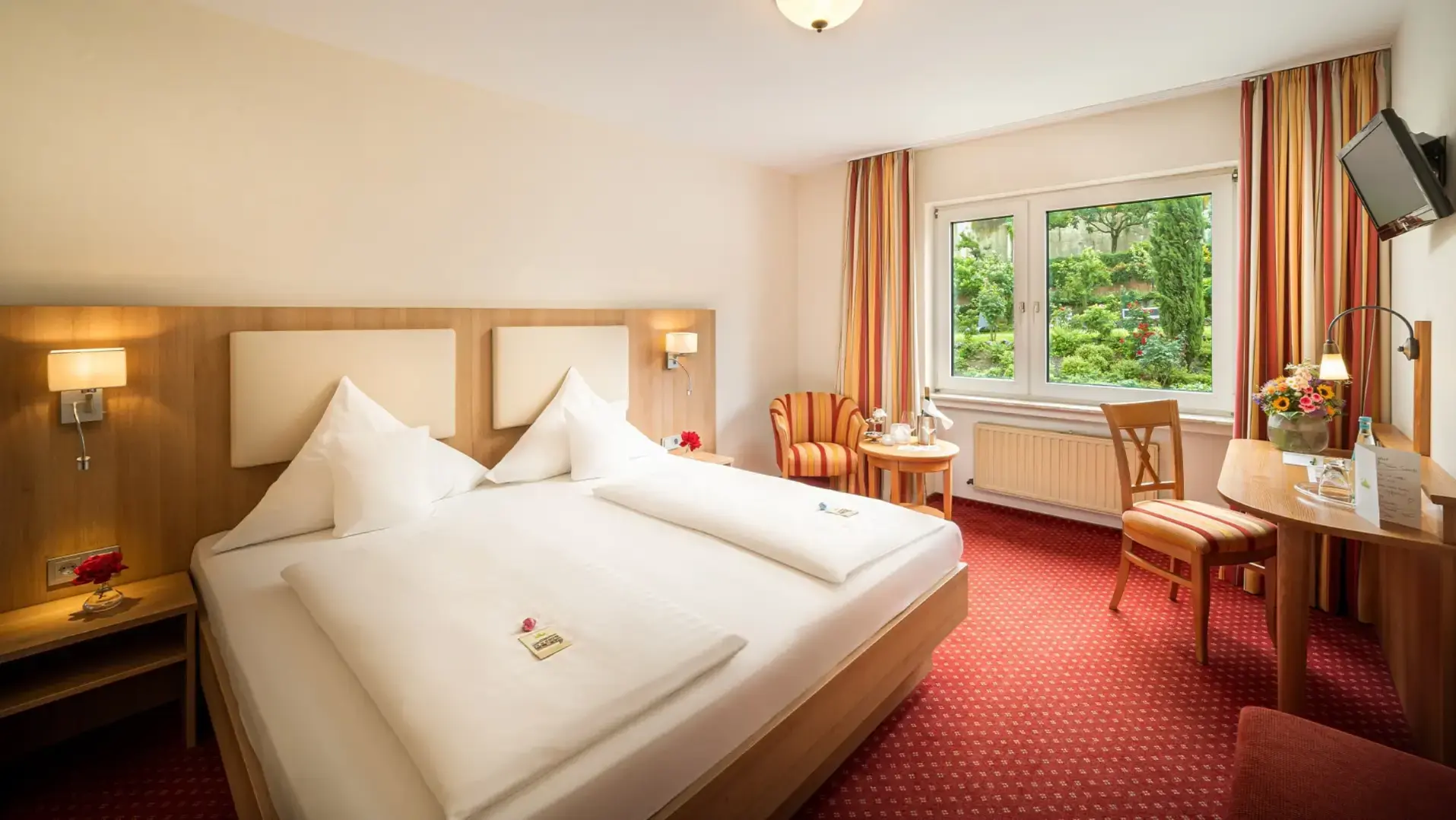 Helles Hotelzimmer mit Doppelbett und Blick ins Grüne