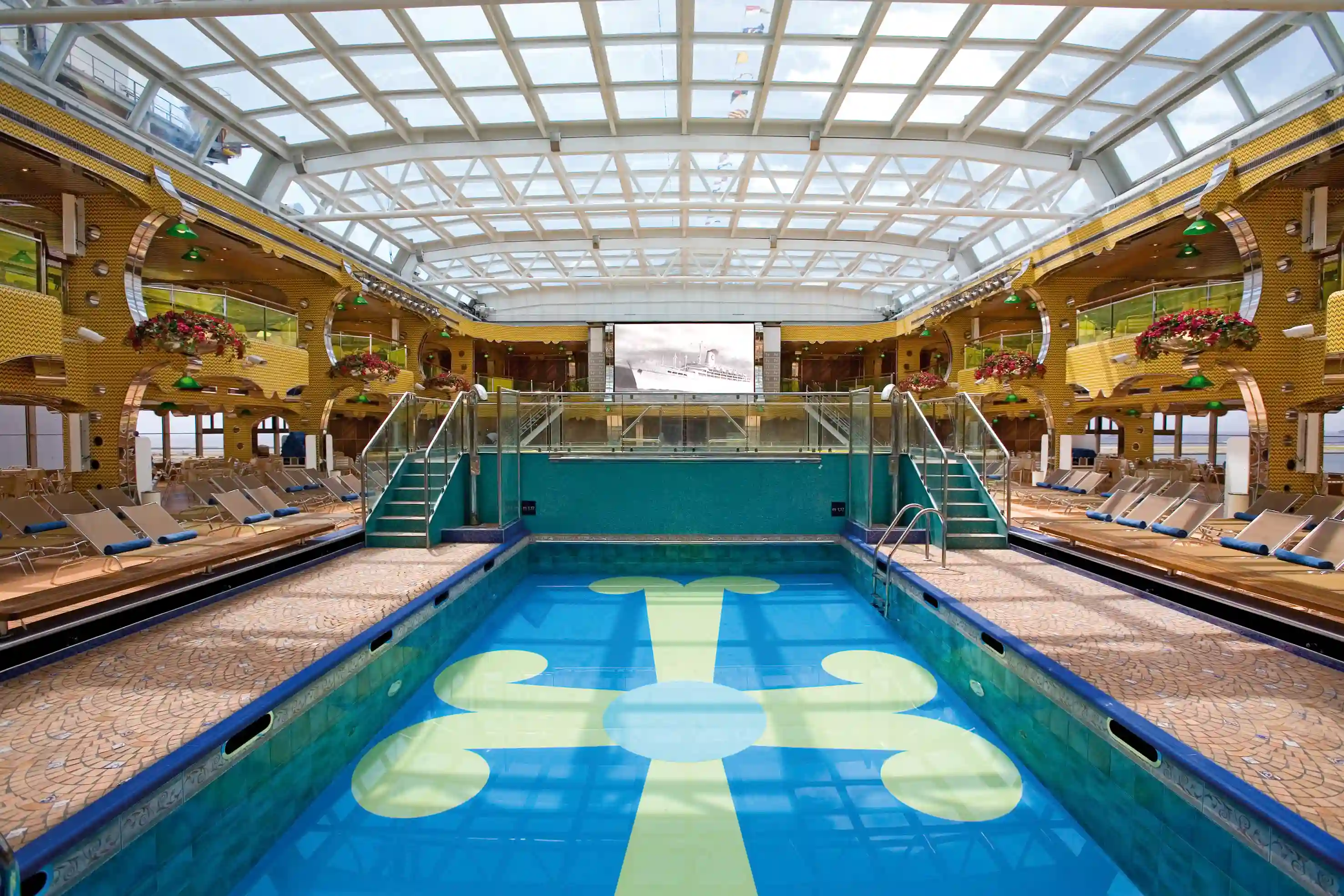 Poolbereich mit Treppen, Liegestühlen und Glasdach