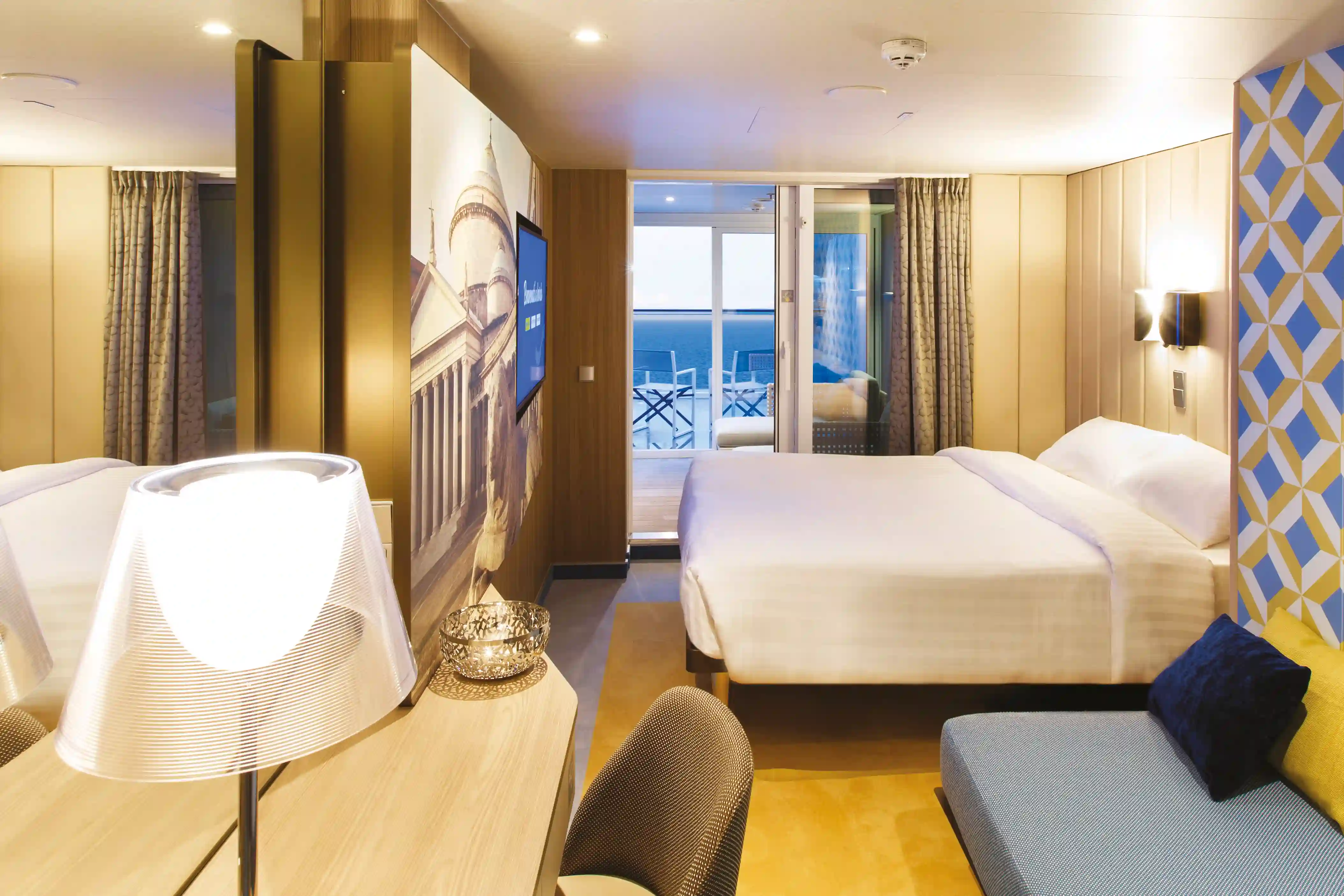 Moderne Balkonkabine der Costa Smeralda mit Doppelbett, Sitzsofa und Blick auf das Meer