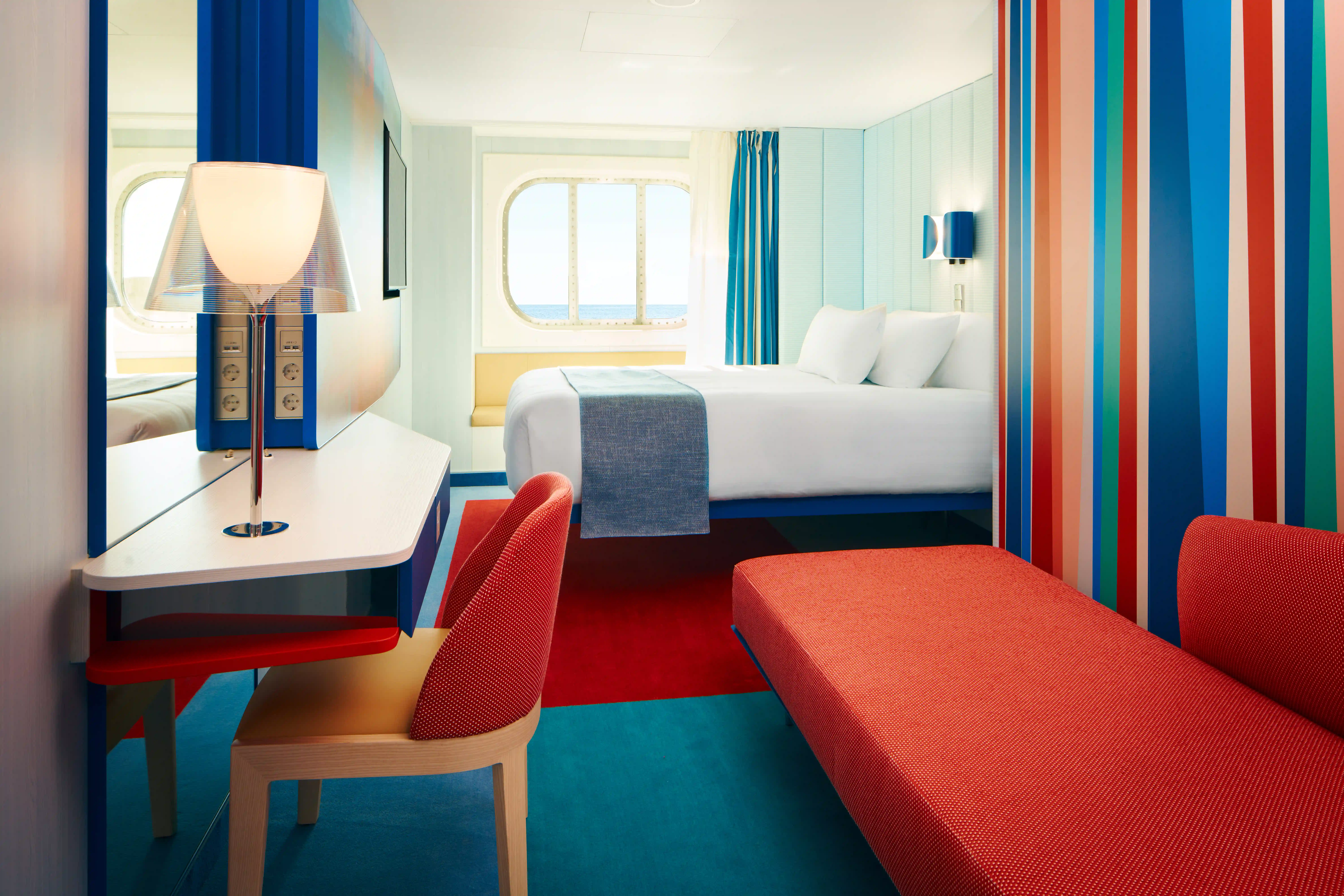Cabine extérieure sur navire de croisière avec lit double, canapé et fenêtre avec vue sur la mer