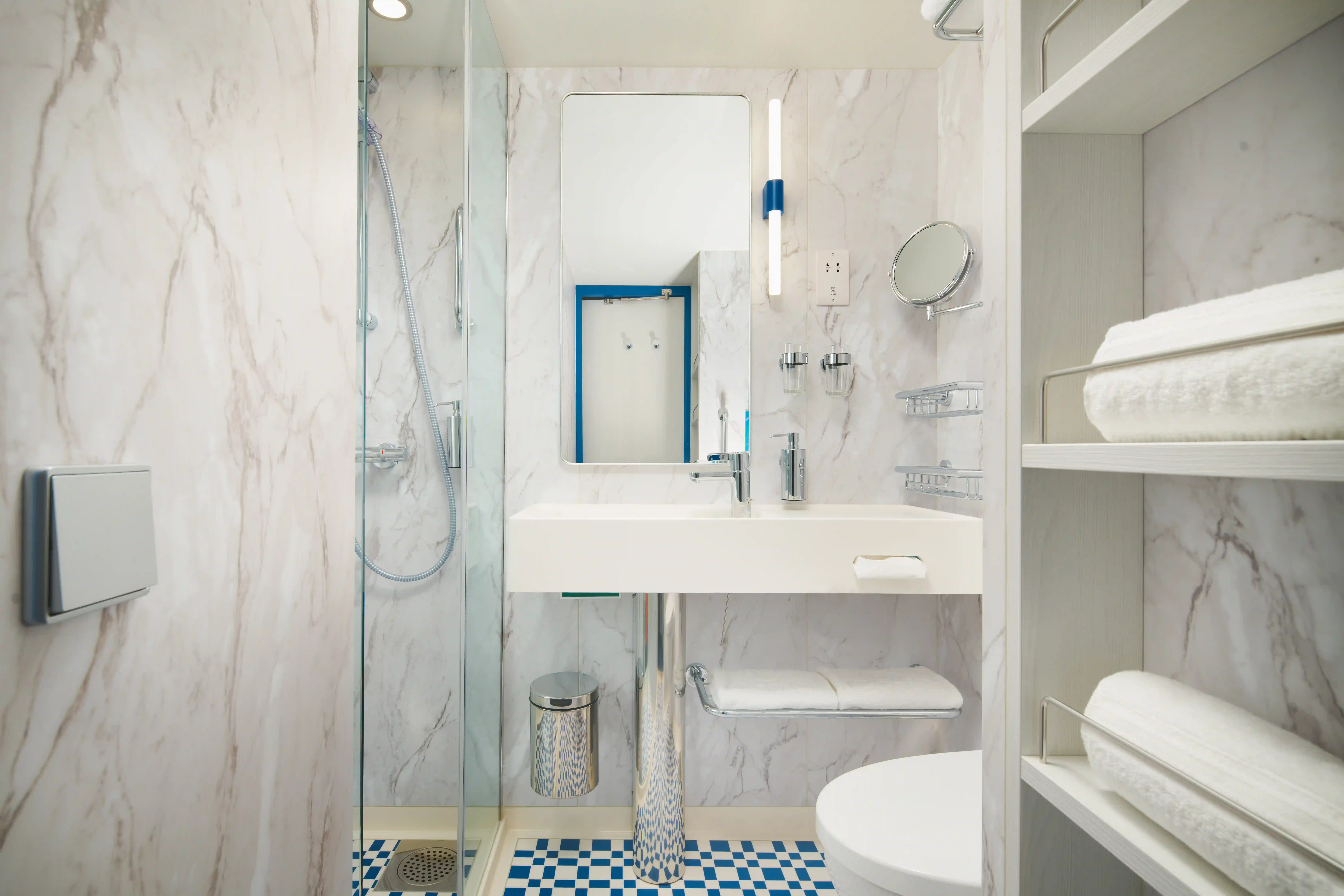 Salle de bain de cabine sur navire de croisière avec douche, lavabo et serviettes