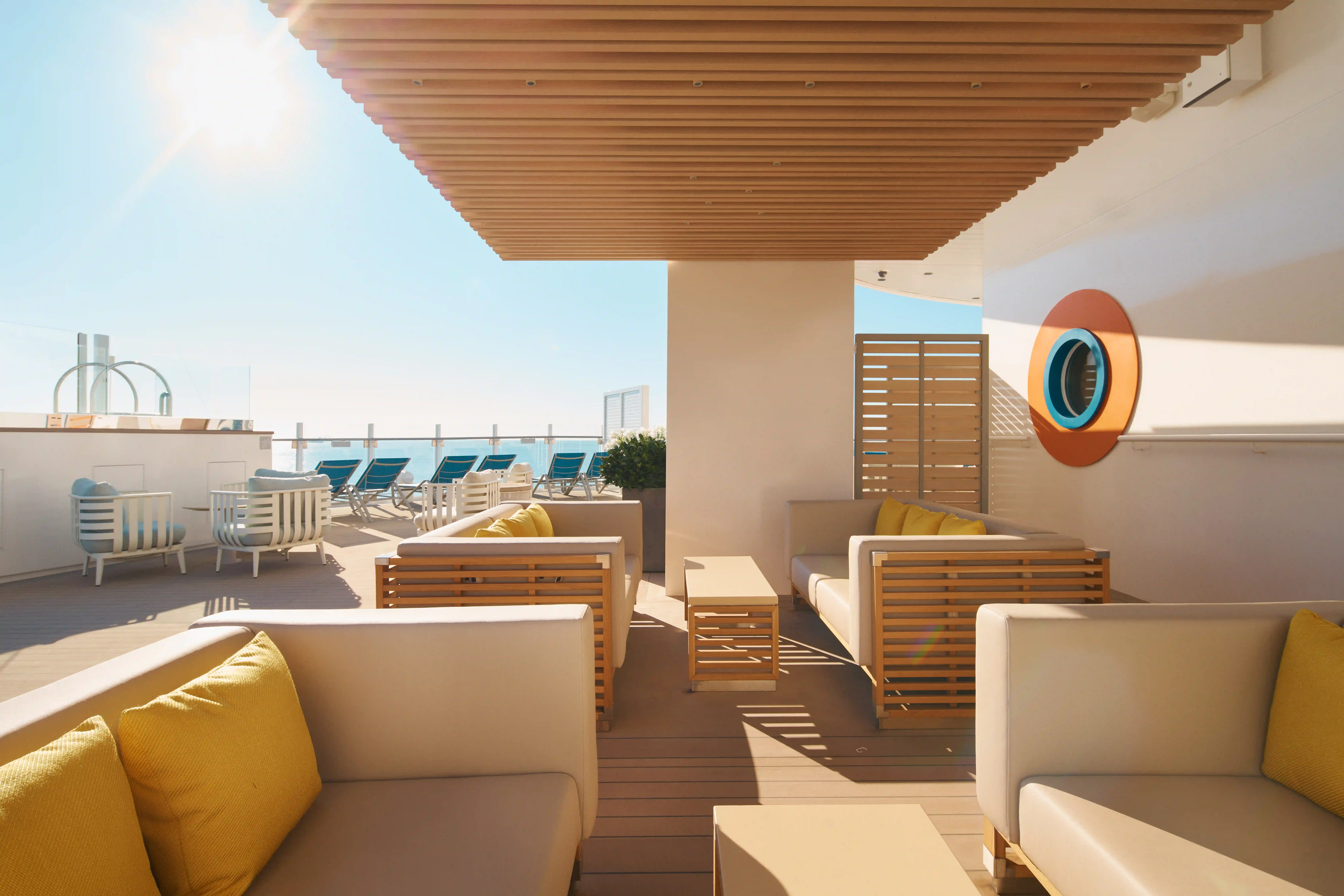 Salon extérieur sur navire de croisière avec fauteuils, plantes et vue sur la mer