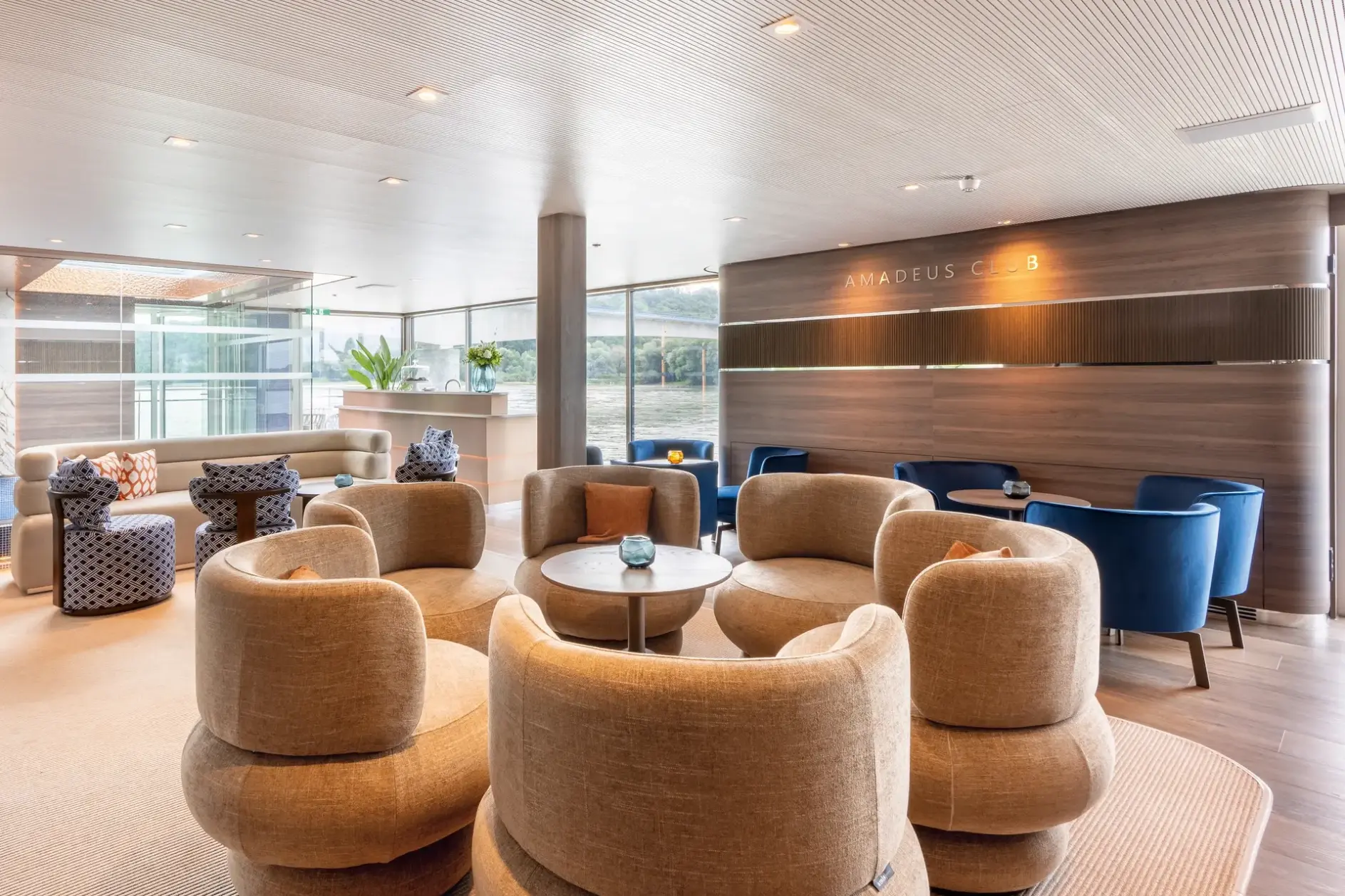 Lounge an Bord eines Flusskreuzfahrtschiffes mit Sitzgruppen und Panoramafenstern
